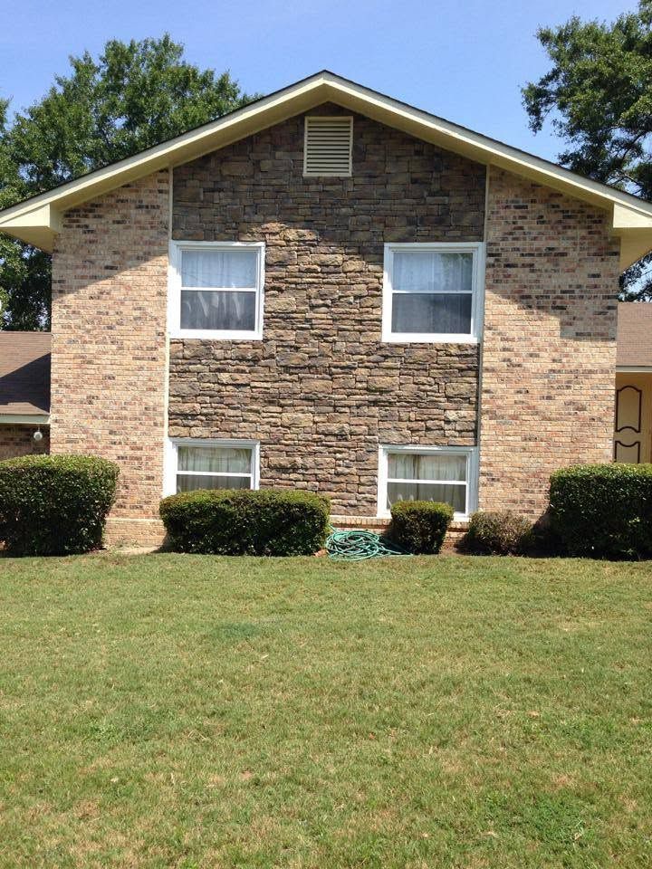Two-story brick apartment building with white-trimmed windows and a grassy front lawn