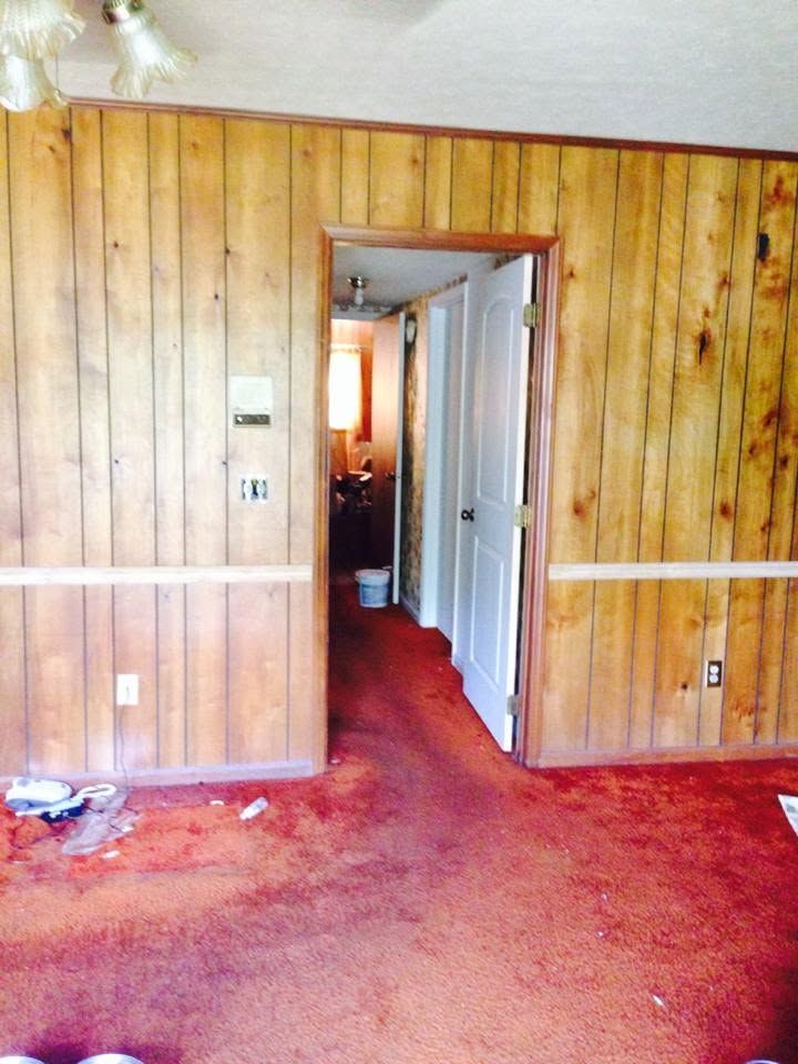 Wood-paneled room with red carpet and an open doorway leading into a lit hallway