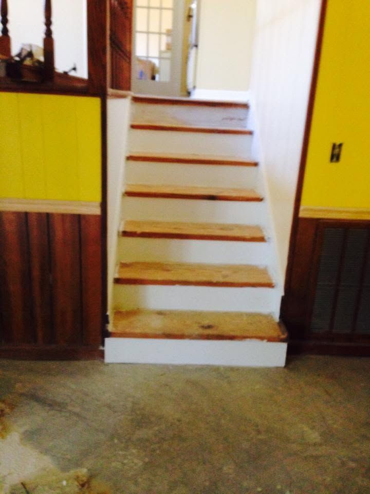 Indoor staircase with white steps and wooden trim between yellow paneled walls.