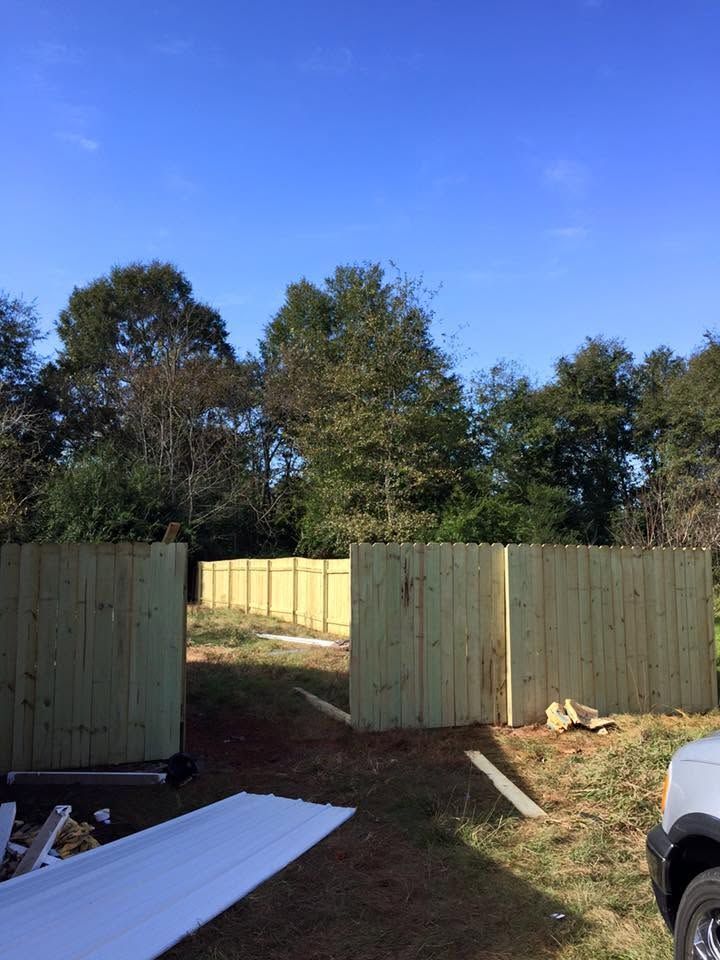 New wooden fence panels in a backyard under a clear blue sky
