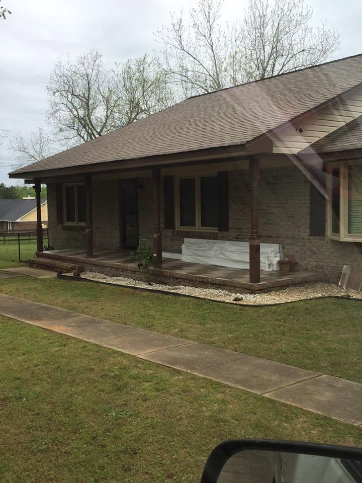 Single-story brick house with a covered porch, front walkway, and lawn on an overcast day