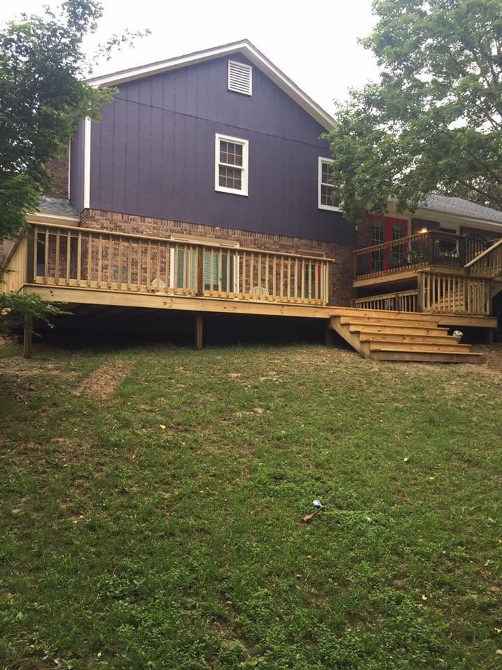 Purple house with a wooden porch and steps on a grassy slope