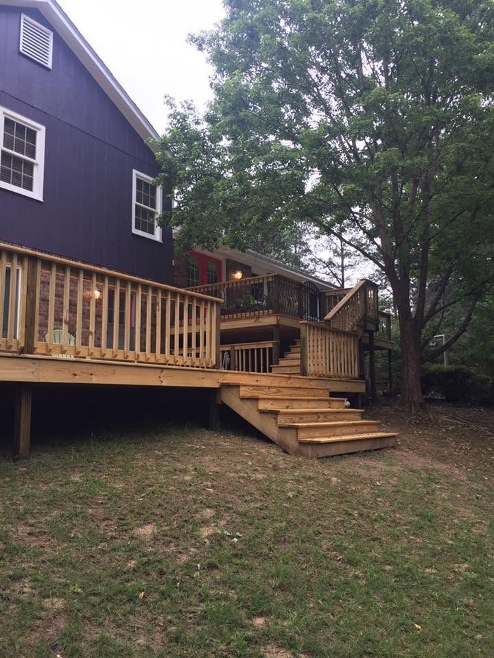 Wooden deck and steps beside a dark house in a wooded backyard.