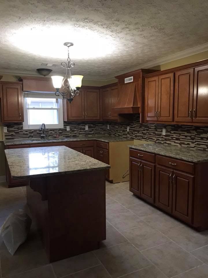 Modern kitchen with dark wood cabinets, granite counters, tiled backsplash, and a central island.
