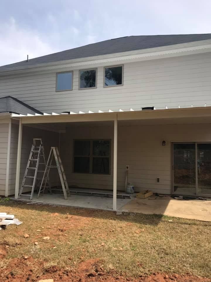 House exterior with open porch, ladder, and workers doing roof or siding repairs