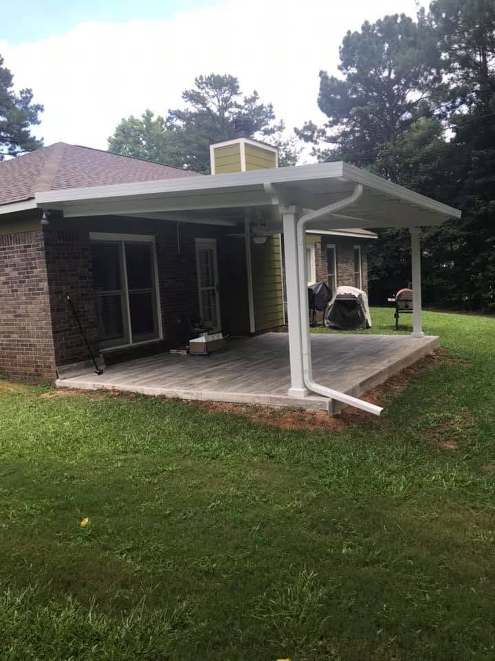 Covered patio with white columns beside a brick house and grassy yard