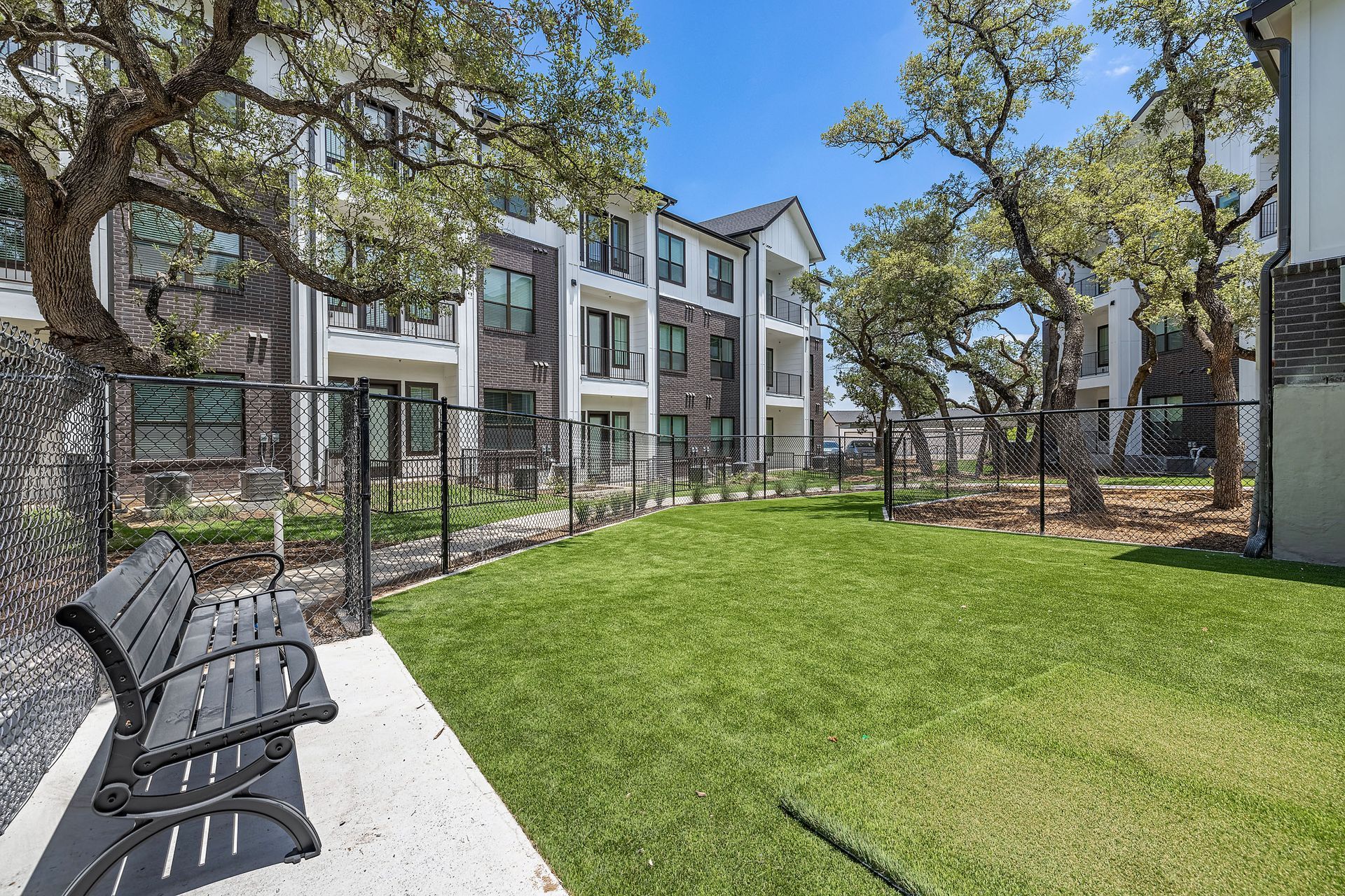 A park bench is sitting in the grass in front of the apartment building at The Avery, which offers apartments for rent in Brushy Creek Austin, TX.