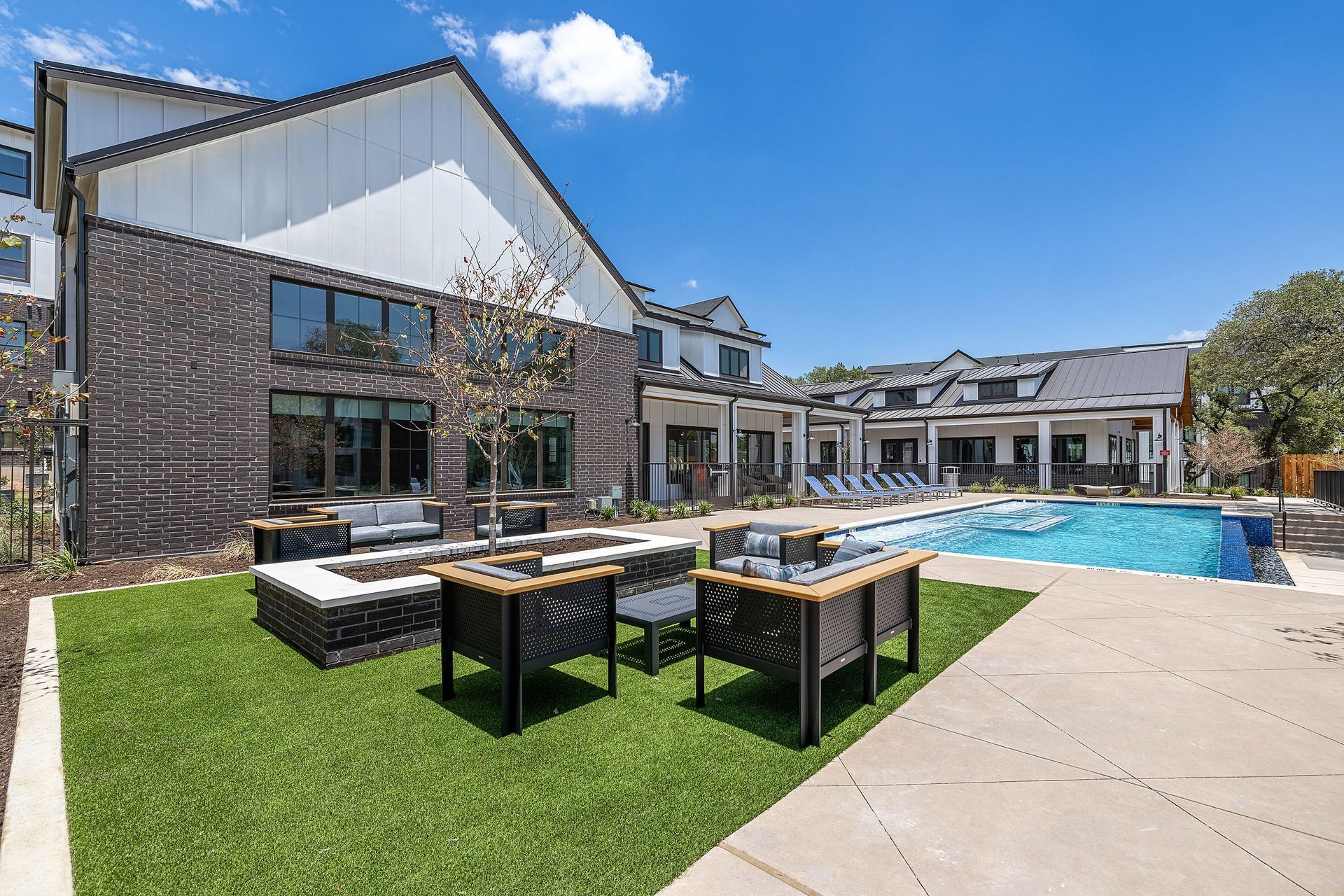 A large apartment building with a swimming pool and a fire pit in front of it at The Avery, which offers apartments for rent in Brushy Creek, Austin, TX.