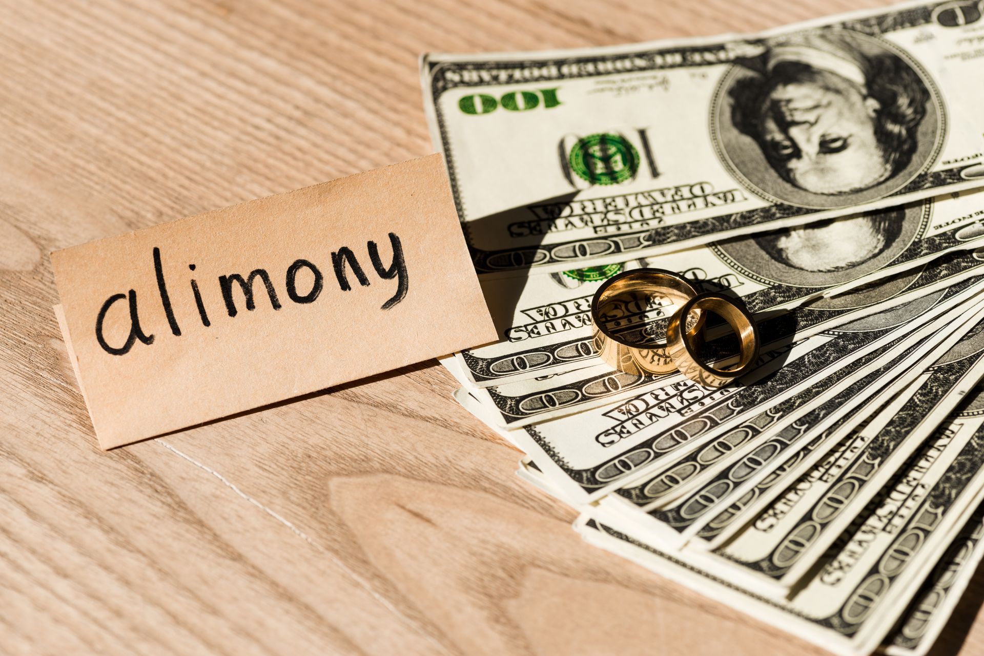 A couple clasp hands over divorce papers, a pen, and rings on a table A couple clasp hands over divorce papers, a pen, and rings on a table
