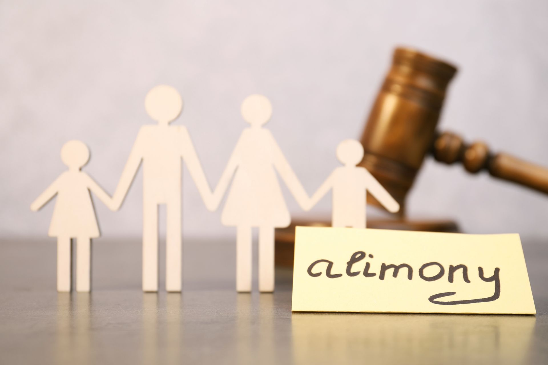 A paper cutout family with a gavel and alimony note at a table, symbolizing legal family matters A paper cutout family with a gavel and alimony note at a table, symbolizing legal family matters
