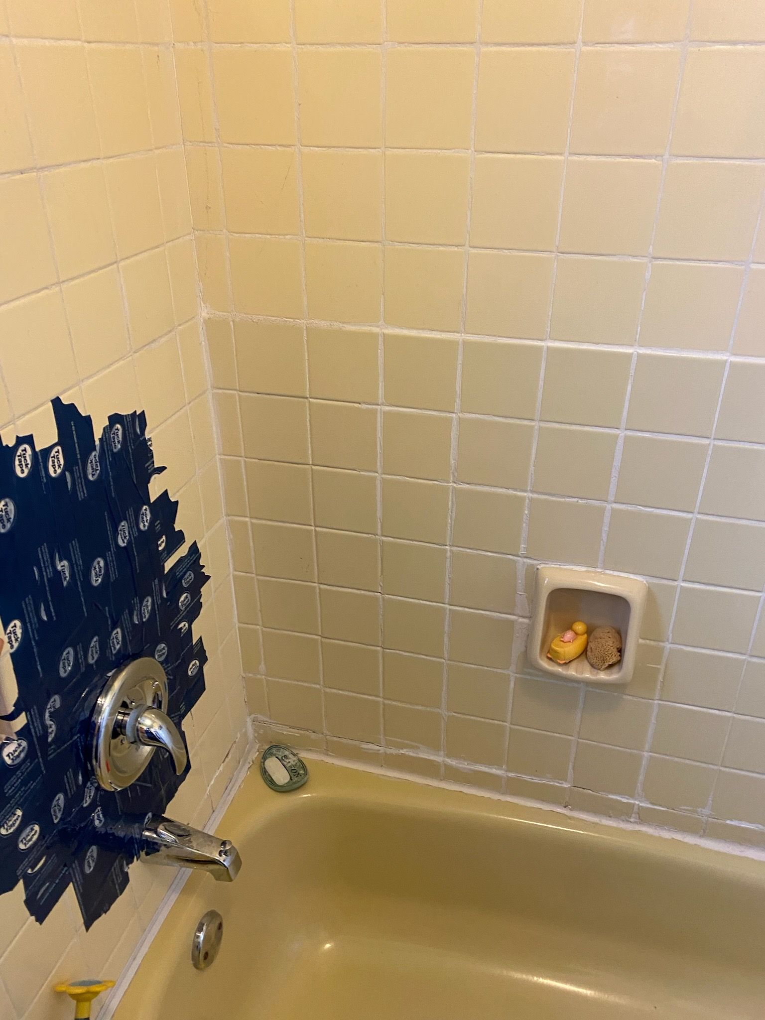 Beige tiled bathtub with a dark blue area near the faucet and a soap dish.