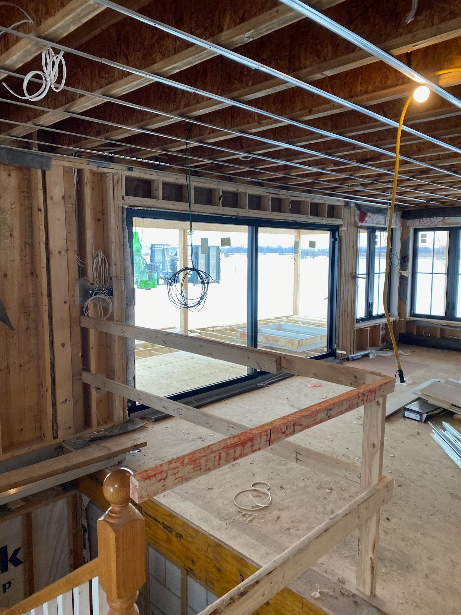 Interior view of a house under construction with wood framing and large windows.