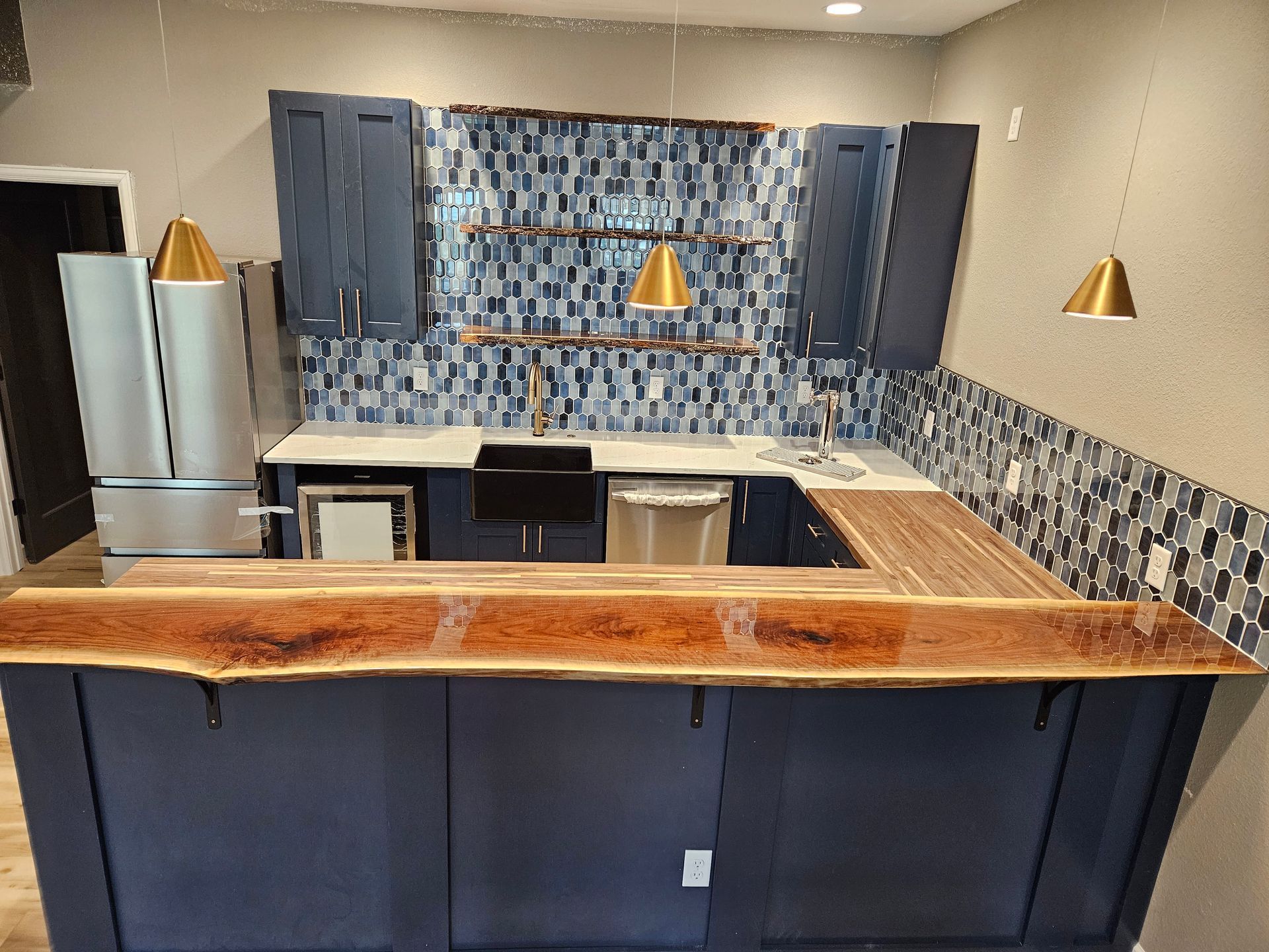 Empty modern kitchen with dark cabinets, wood countertop, and blue mosaic tile backsplash
