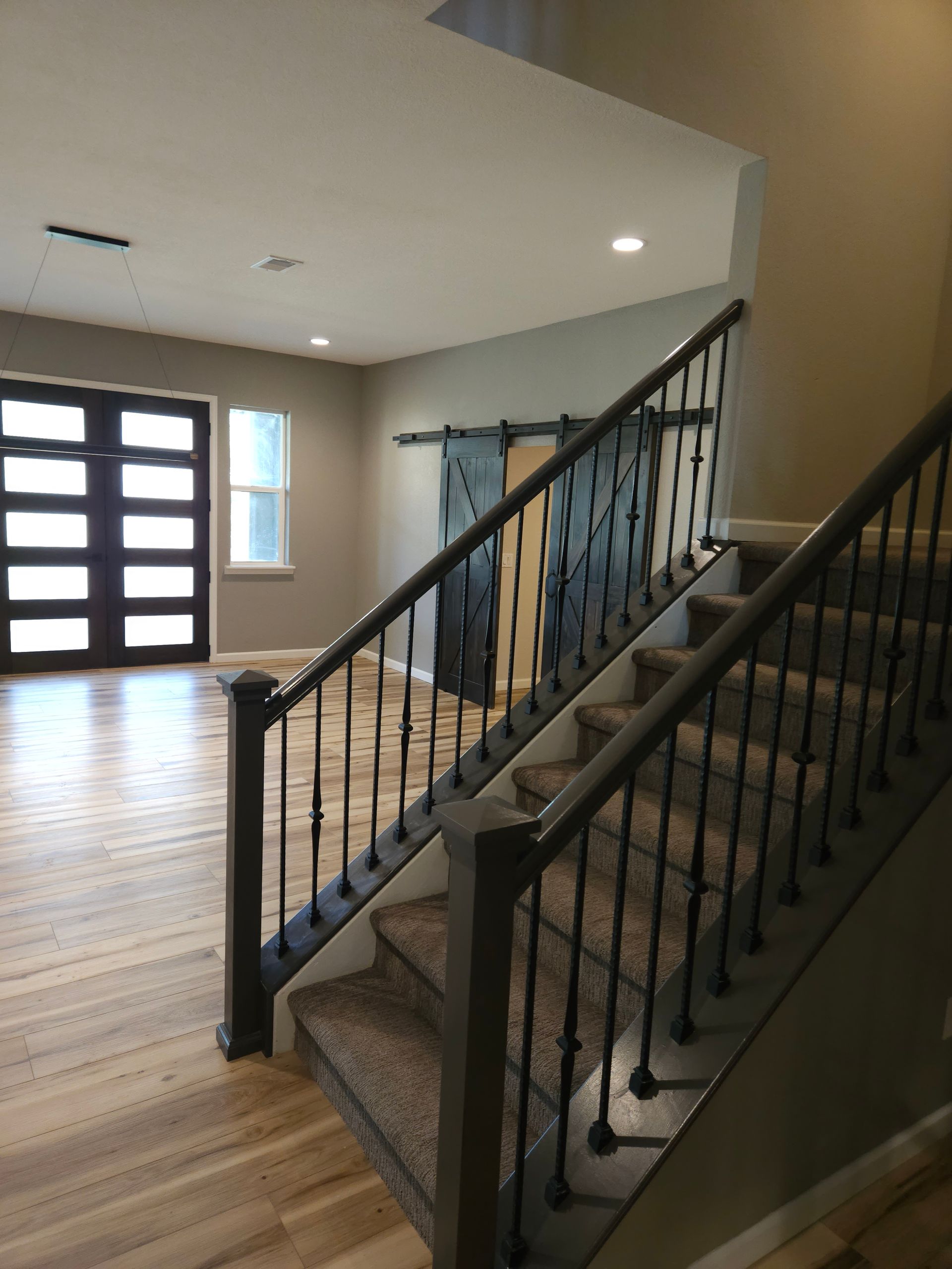 Interior staircase with black railing in a bright modern home foyer