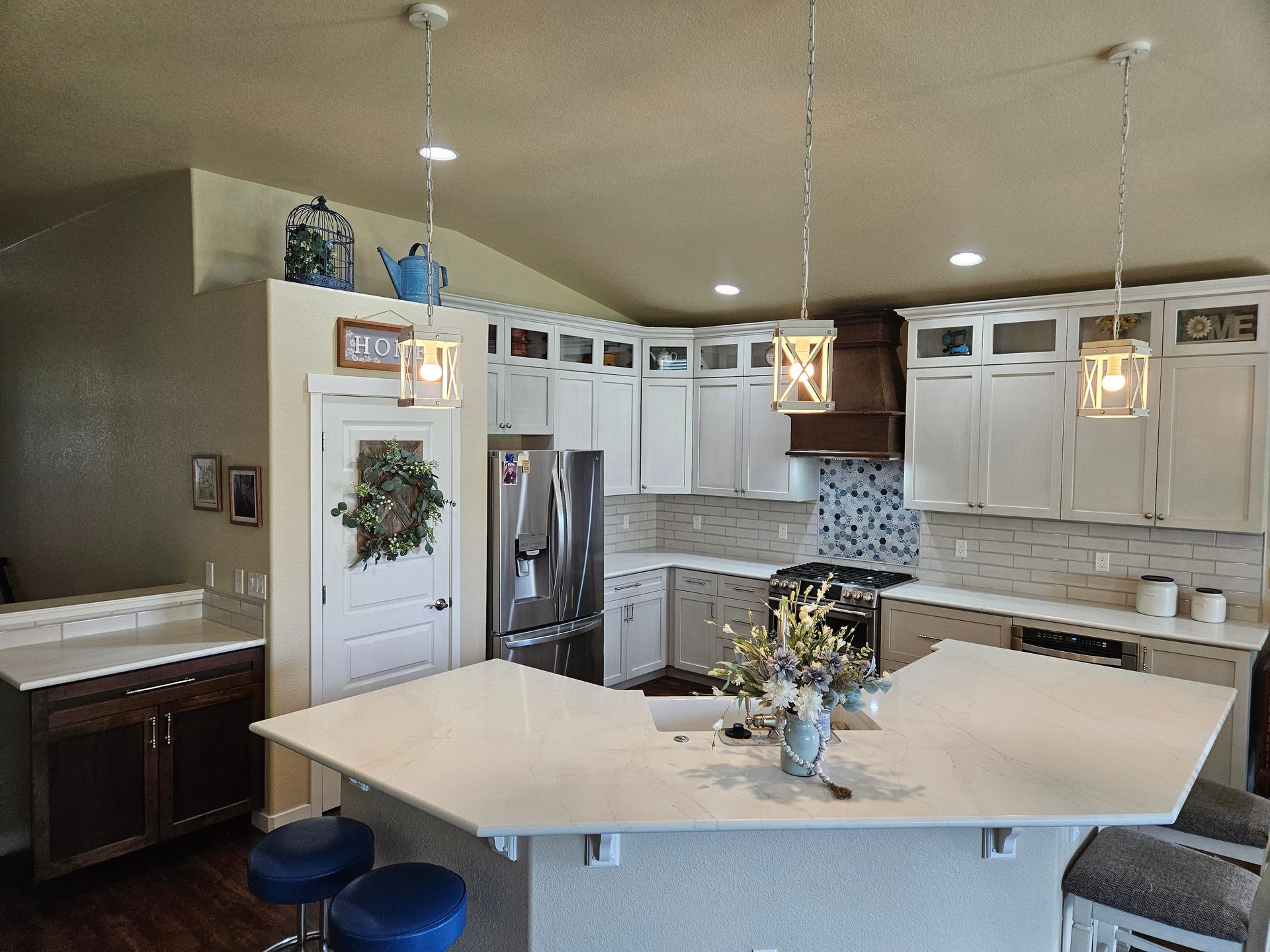 Bright kitchen with white cabinets, central island, hanging lights, and stainless steel appliances