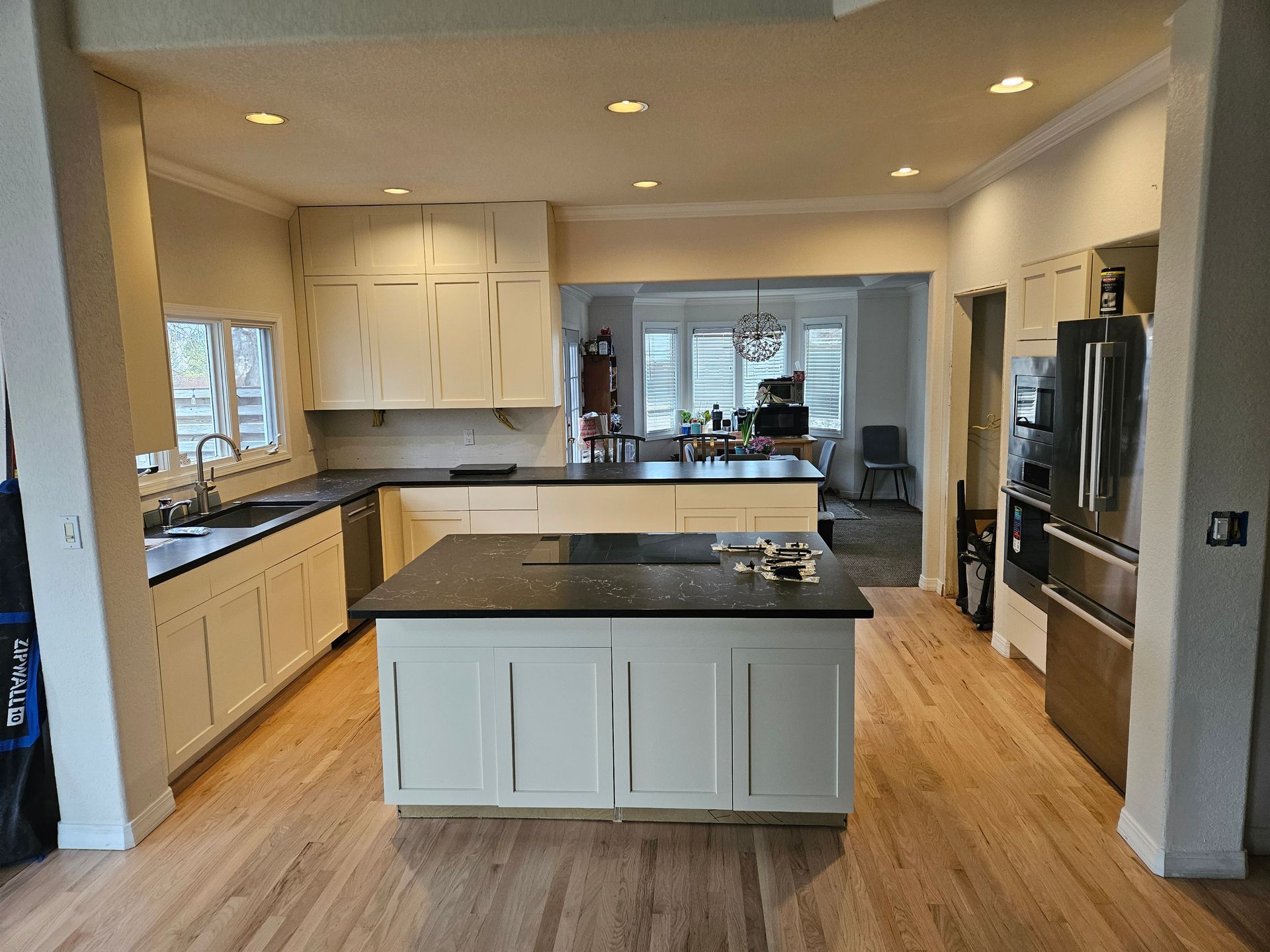 Modern kitchen with white cabinets, black countertops, and a central island under recessed lighting