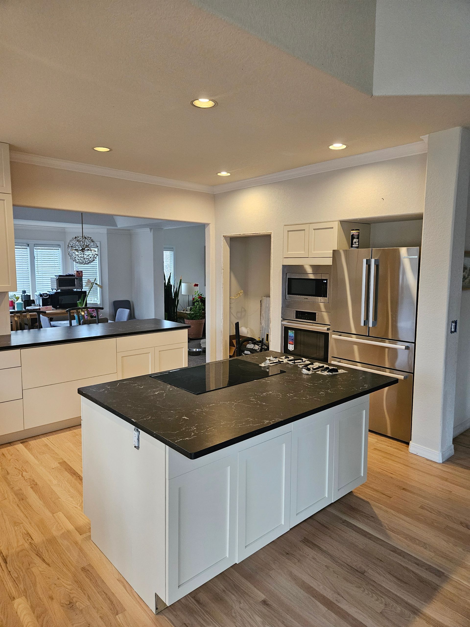 Modern kitchen with white cabinets, black granite island, stainless steel appliances, and hardwood floors