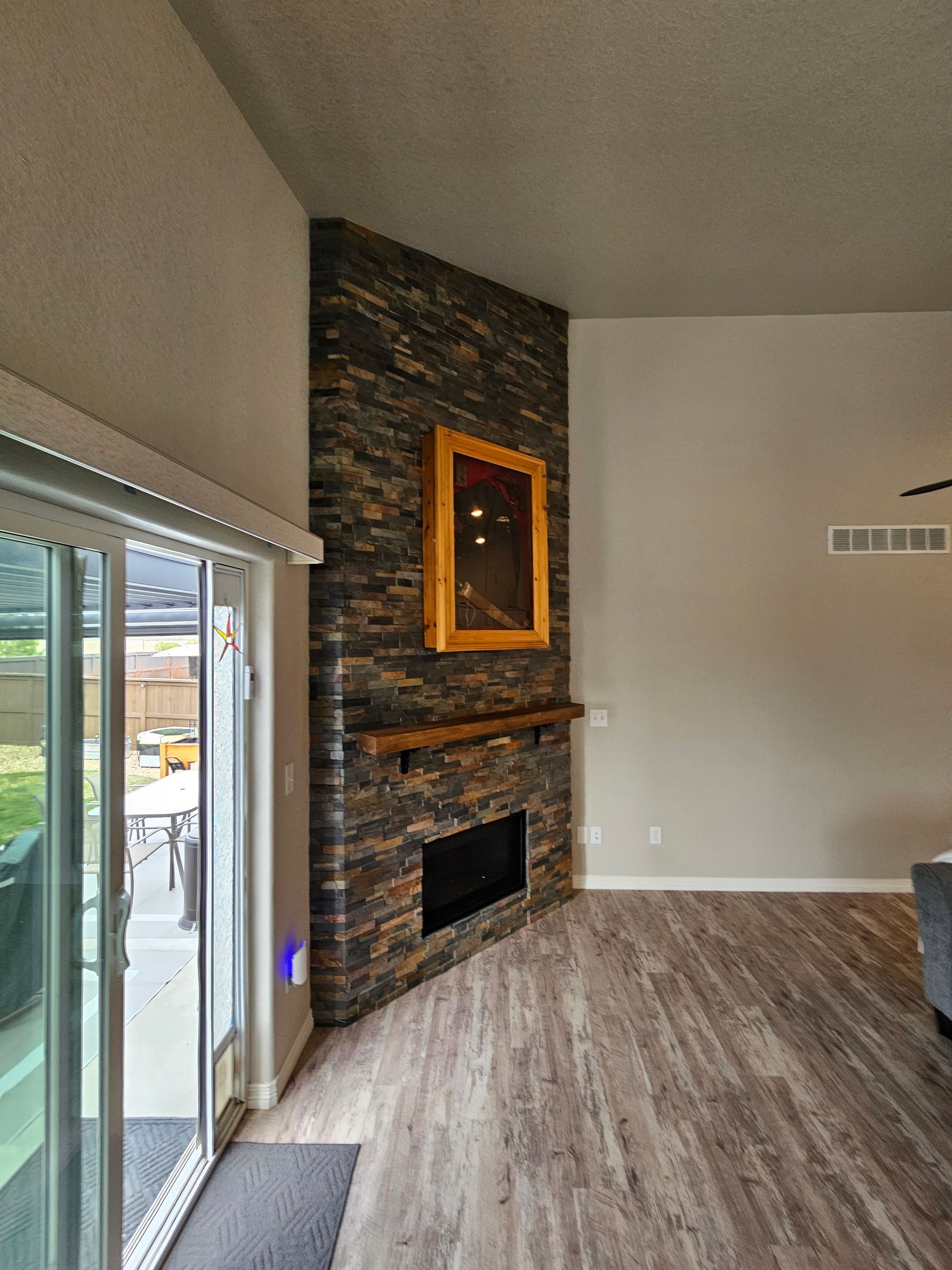Living room with stone fireplace, large sliding glass door, and wood-look flooring