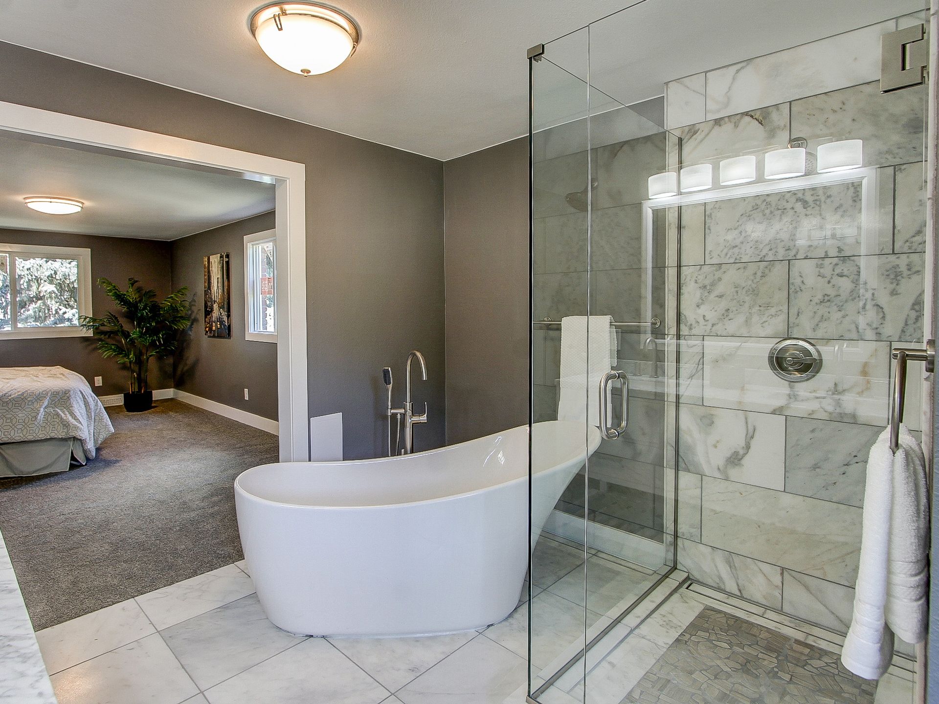 Modern bathroom with glass shower, freestanding tub, and tiled floor