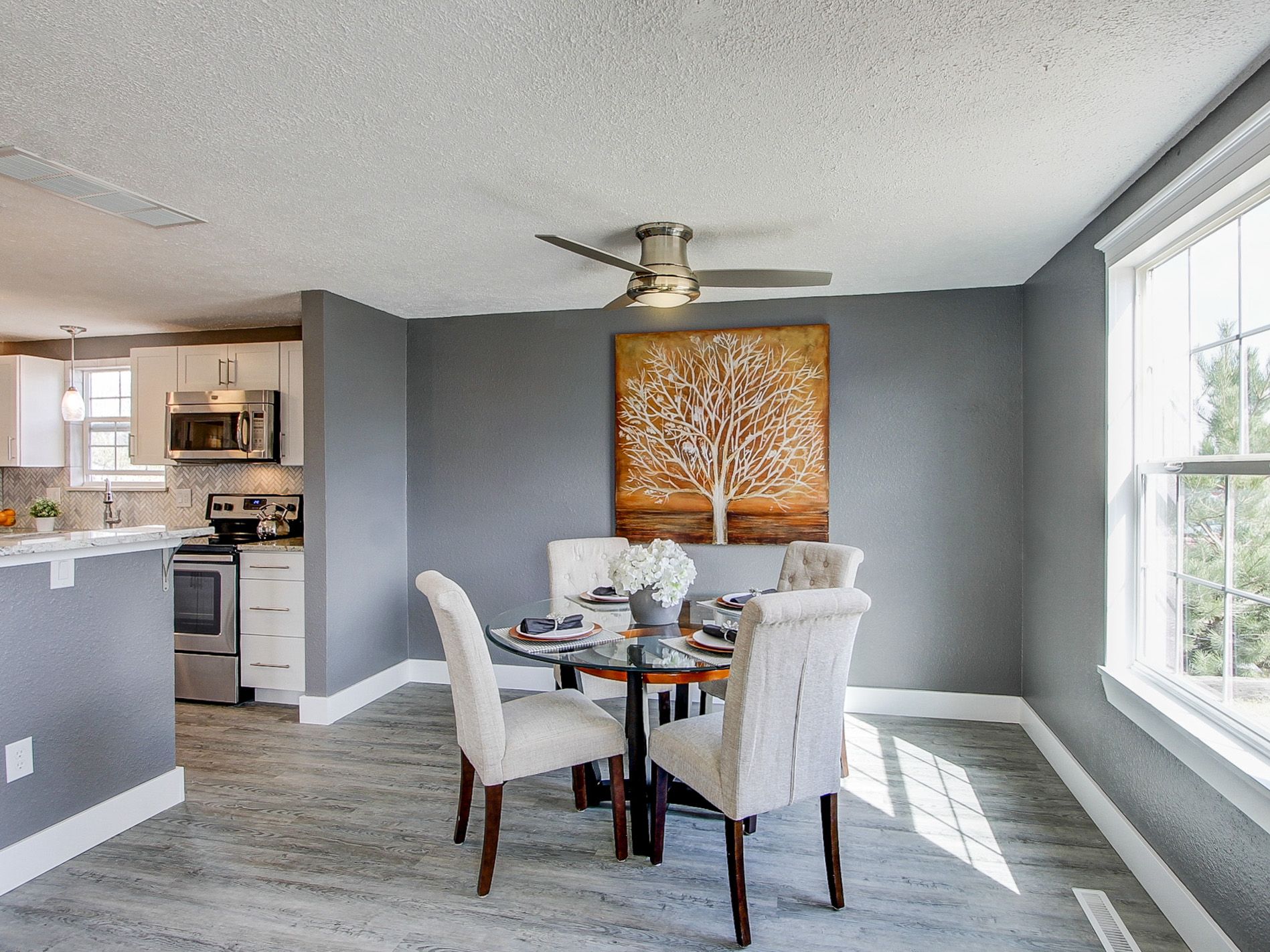 Dining nook with round table, four chairs, gray walls, and bright window light in a modern home
