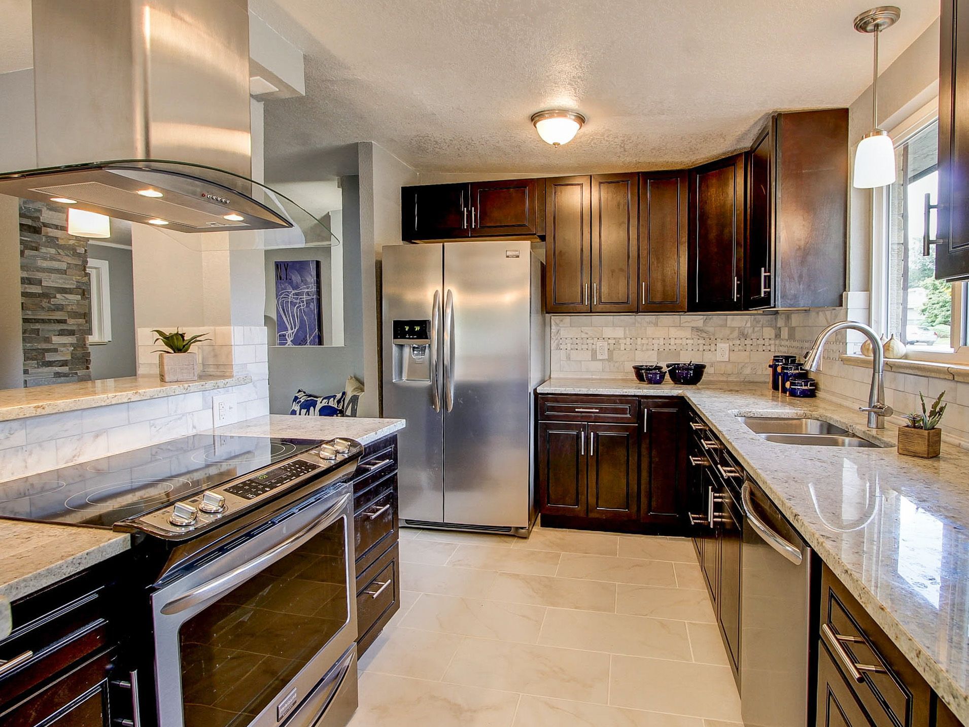 Modern kitchen with stainless steel appliances, dark wood cabinets, and light granite countertops