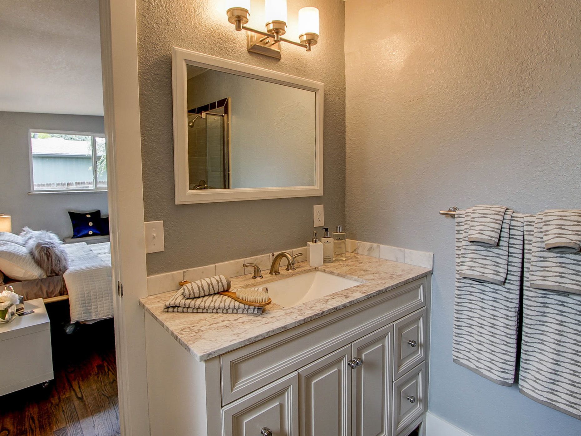 Bathroom vanity with sink, mirror, wall sconce, and woven laundry baskets beside it