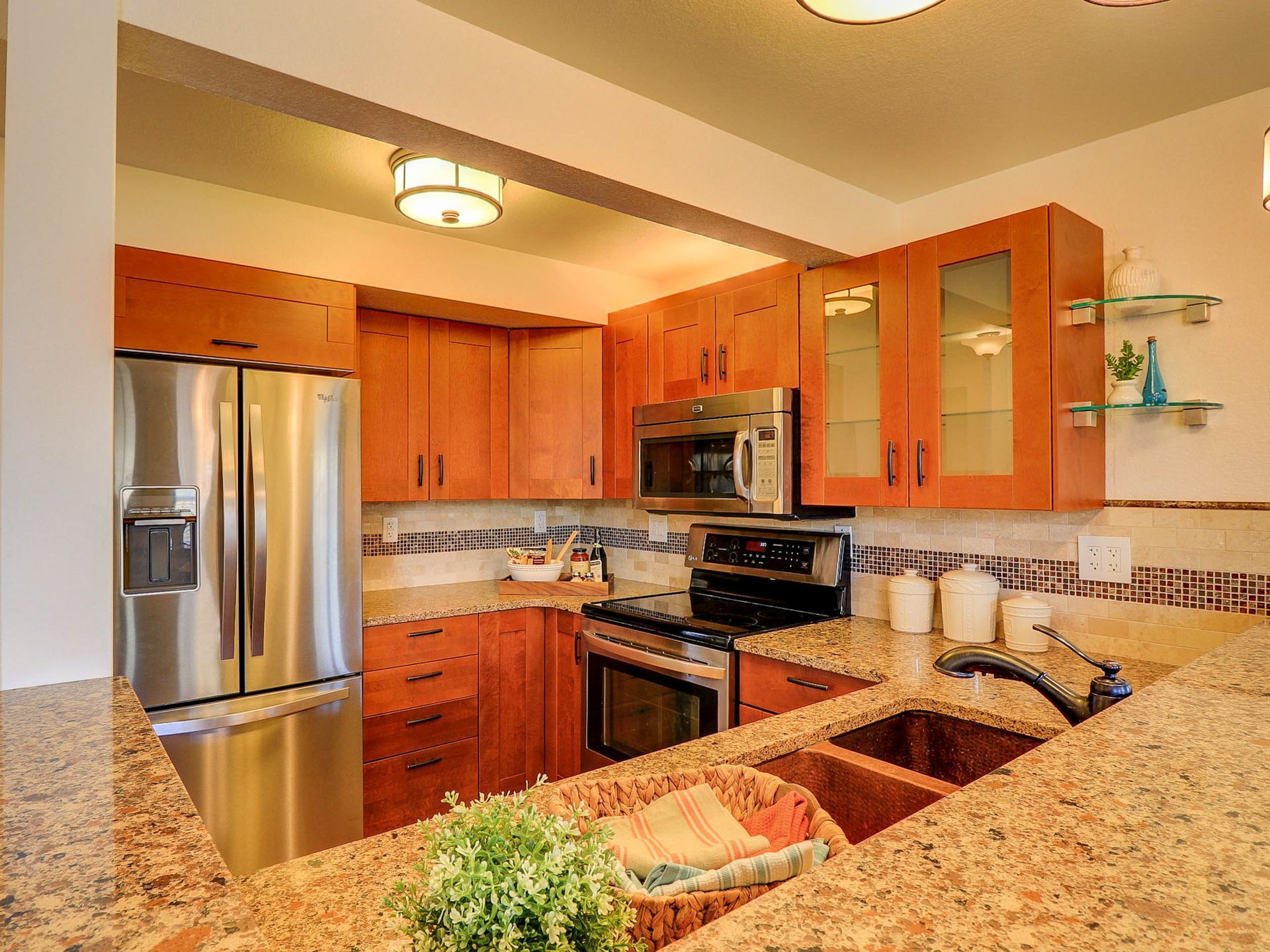 Modern kitchen with stainless steel appliances, wood cabinets, and granite countertops.