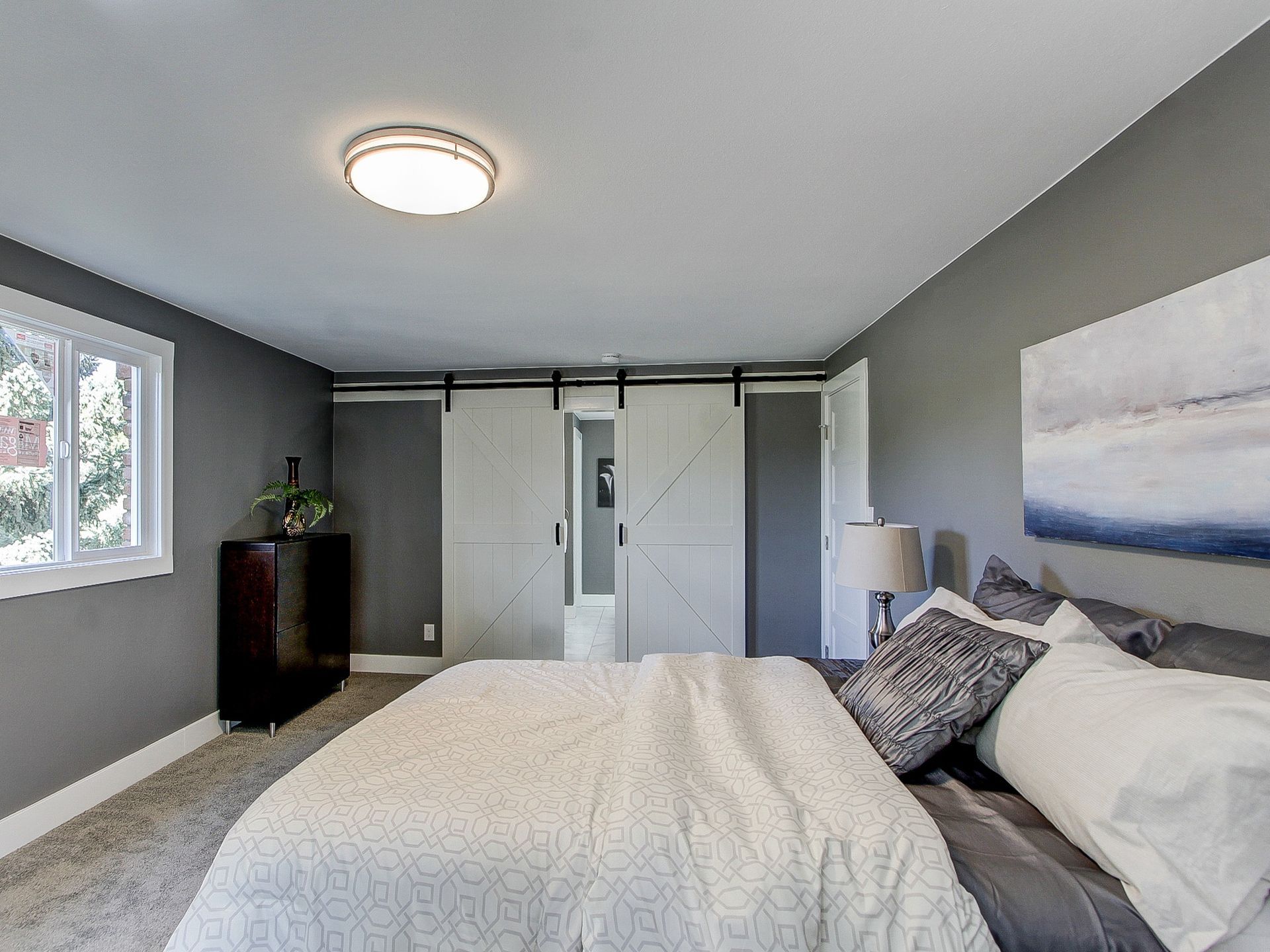 Modern gray bedroom with a bed, closet doors, window, and wall art