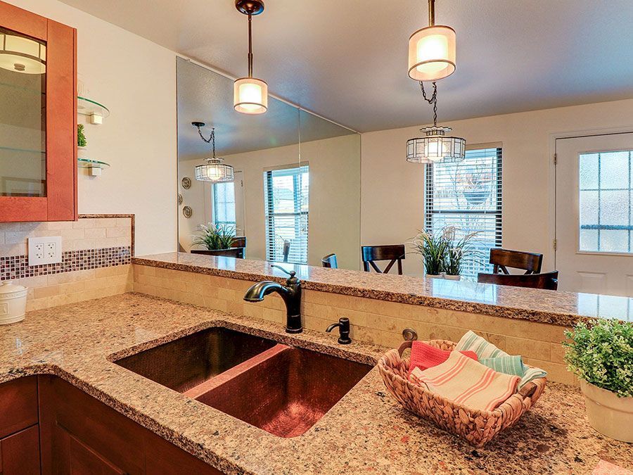 Modern kitchen with granite island, double sink, pendant lights, and dining area in the background