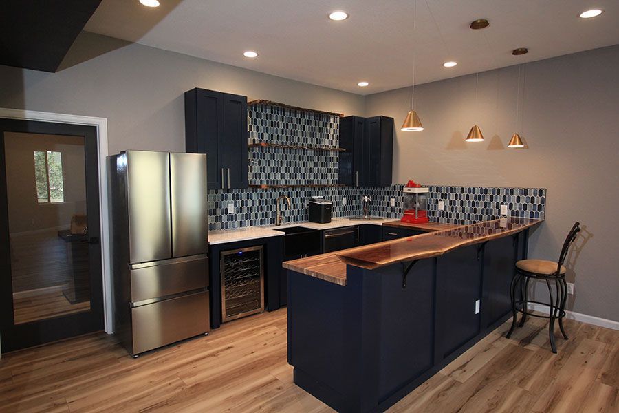 Modern kitchen with stainless steel fridge, navy cabinets, wood island, and patterned backsplash
