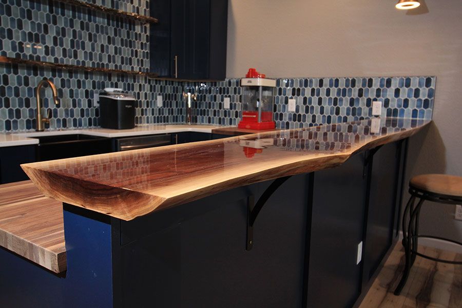 Modern kitchen island with wood countertop, black cabinets, and blue patterned tile backsplash