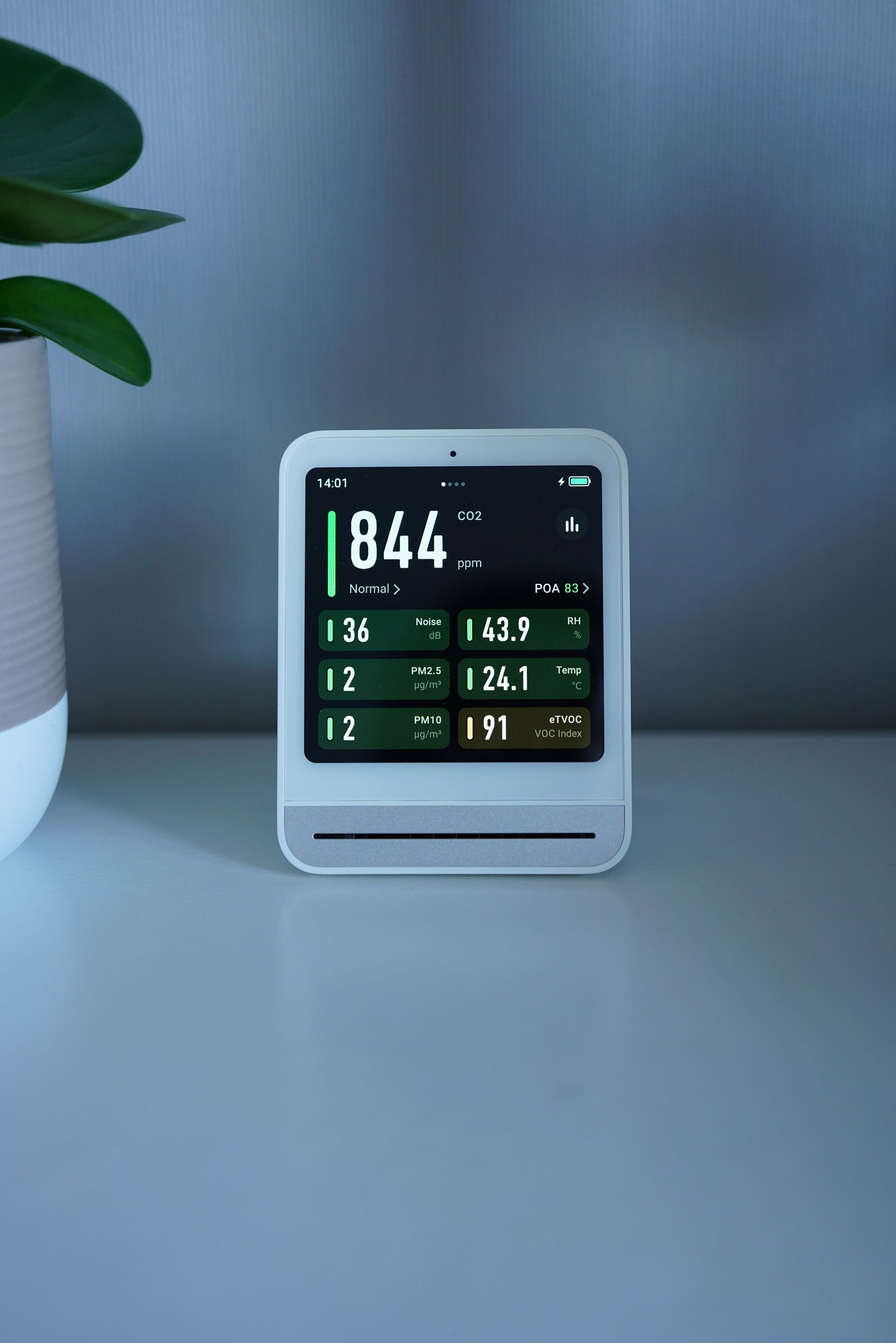 Digital desk display showing 84.4, with smaller green and white readings on a minimalist table.