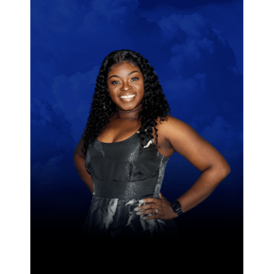 Smiling woman in a black dress posing against a blue studio backdrop