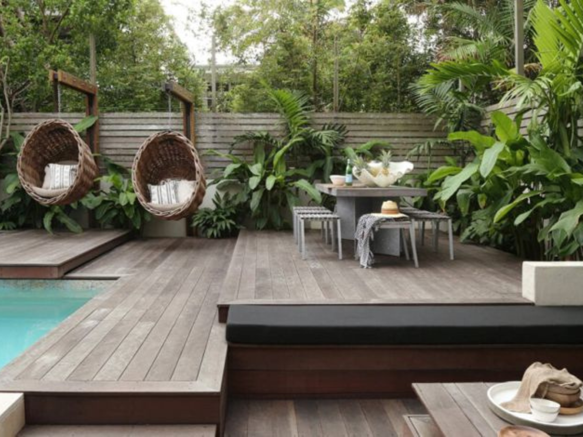 A wooden deck with a table and chairs next to a swimming pool