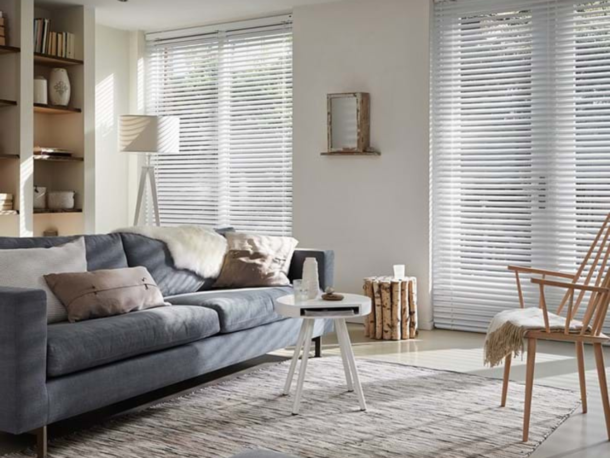 A living room with a couch , chair , table and blinds.