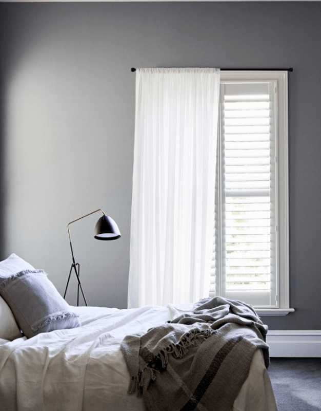 A bedroom with a bed a lamp and a window