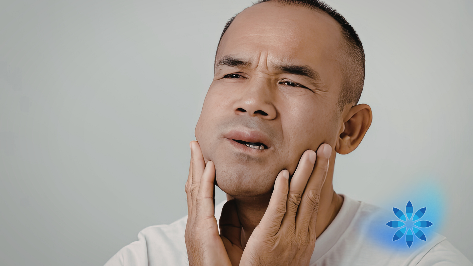 Person grimacing and holding both cheeks, suggesting toothache; blue tooth icon at right.