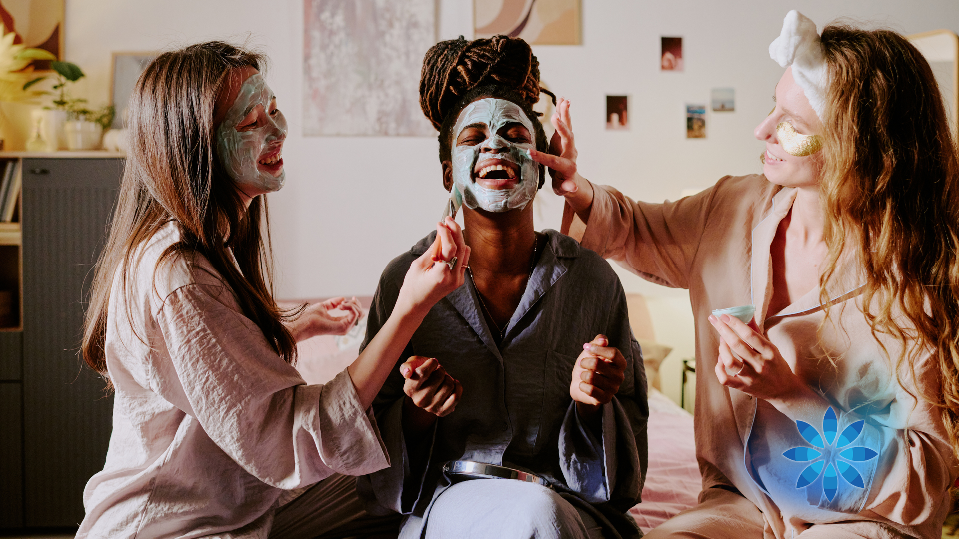 Three people with face masks sit together, laughing and smiling in a bright room.