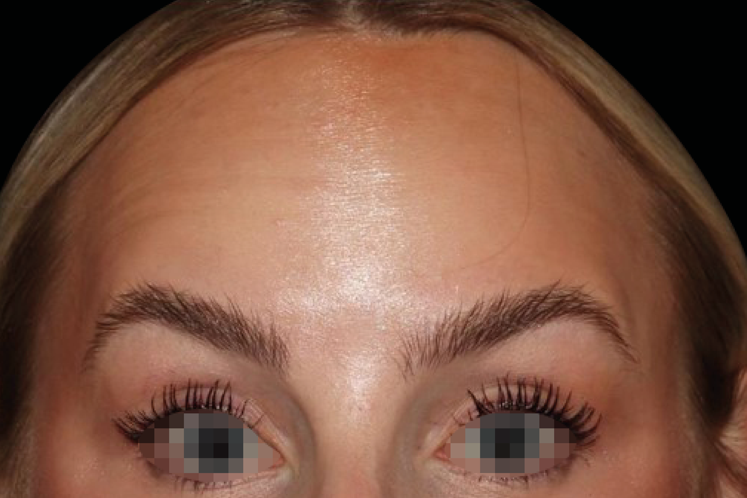 Close-up of a forehead and eyes with makeup, eyebrows, and a shiny skin finish