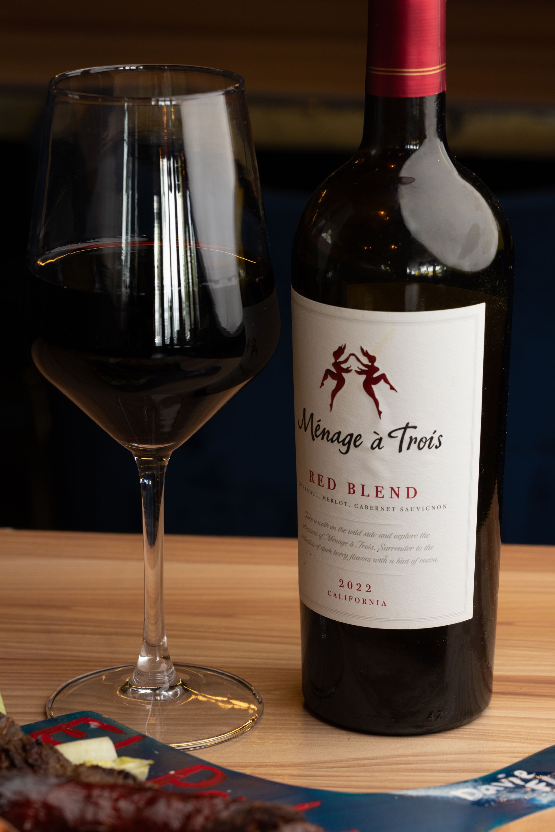 A glass of red wine and a bottle with a label