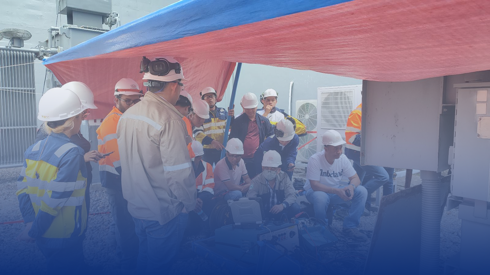 A group of construction workers are standing under a red and blue tarp.