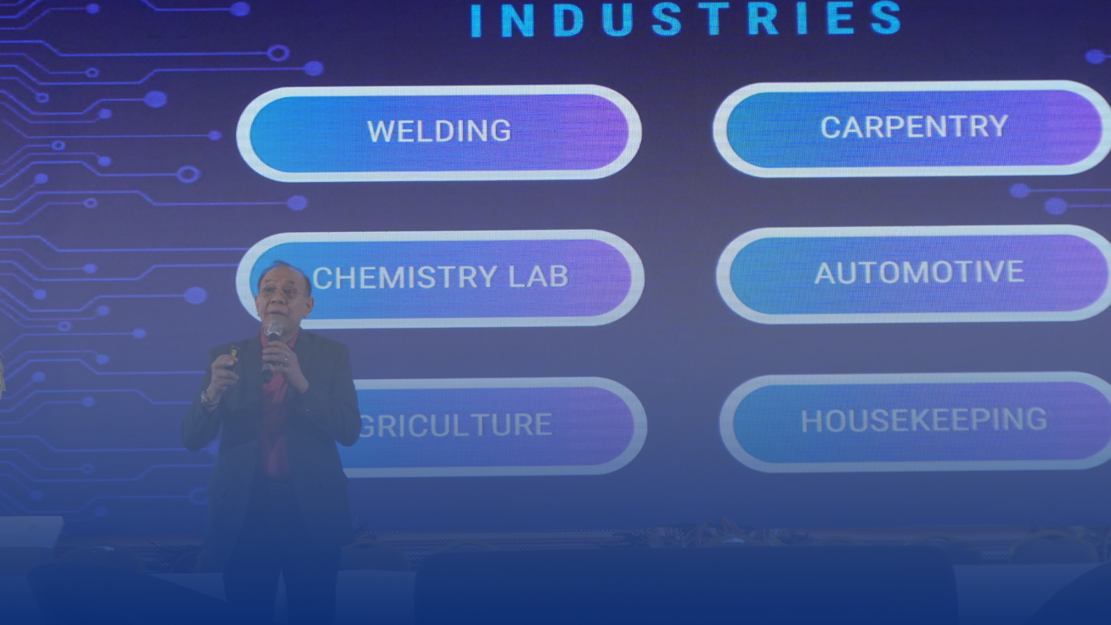 A man is standing in front of a screen with buttons for different industries.