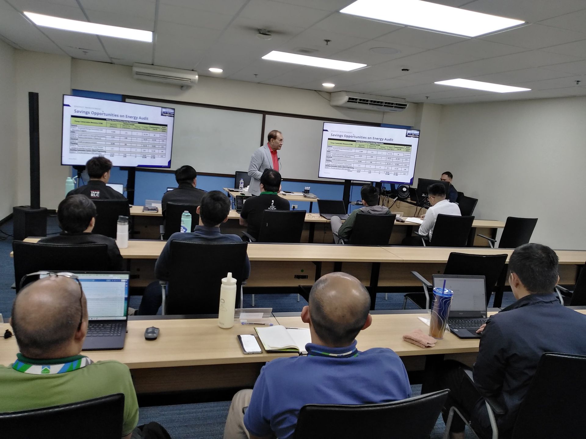 A man is giving a presentation to a group of people in a classroom.