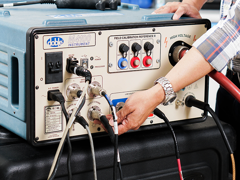 A person is plugging wires into a device that says ' high voltage ' on it