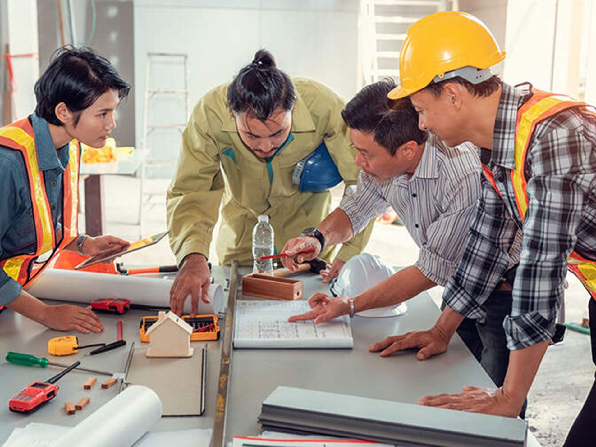 A group of construction workers are looking at a blueprint on a table.