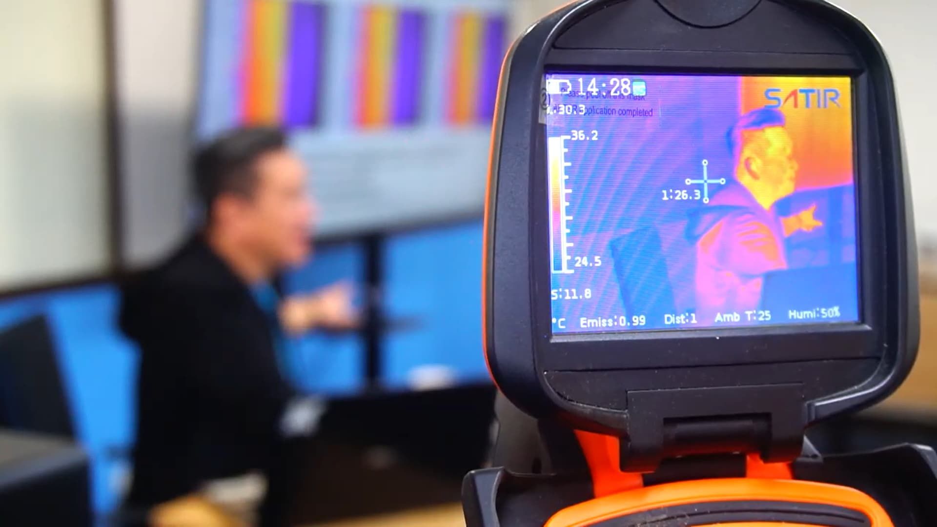 A man is sitting in front of a thermal camera.