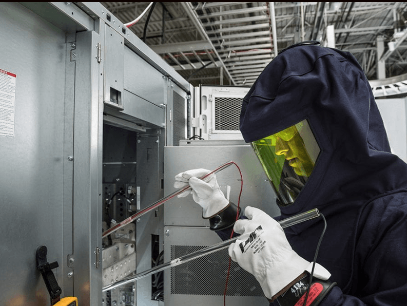 A man in a protective suit is working on an electrical box.