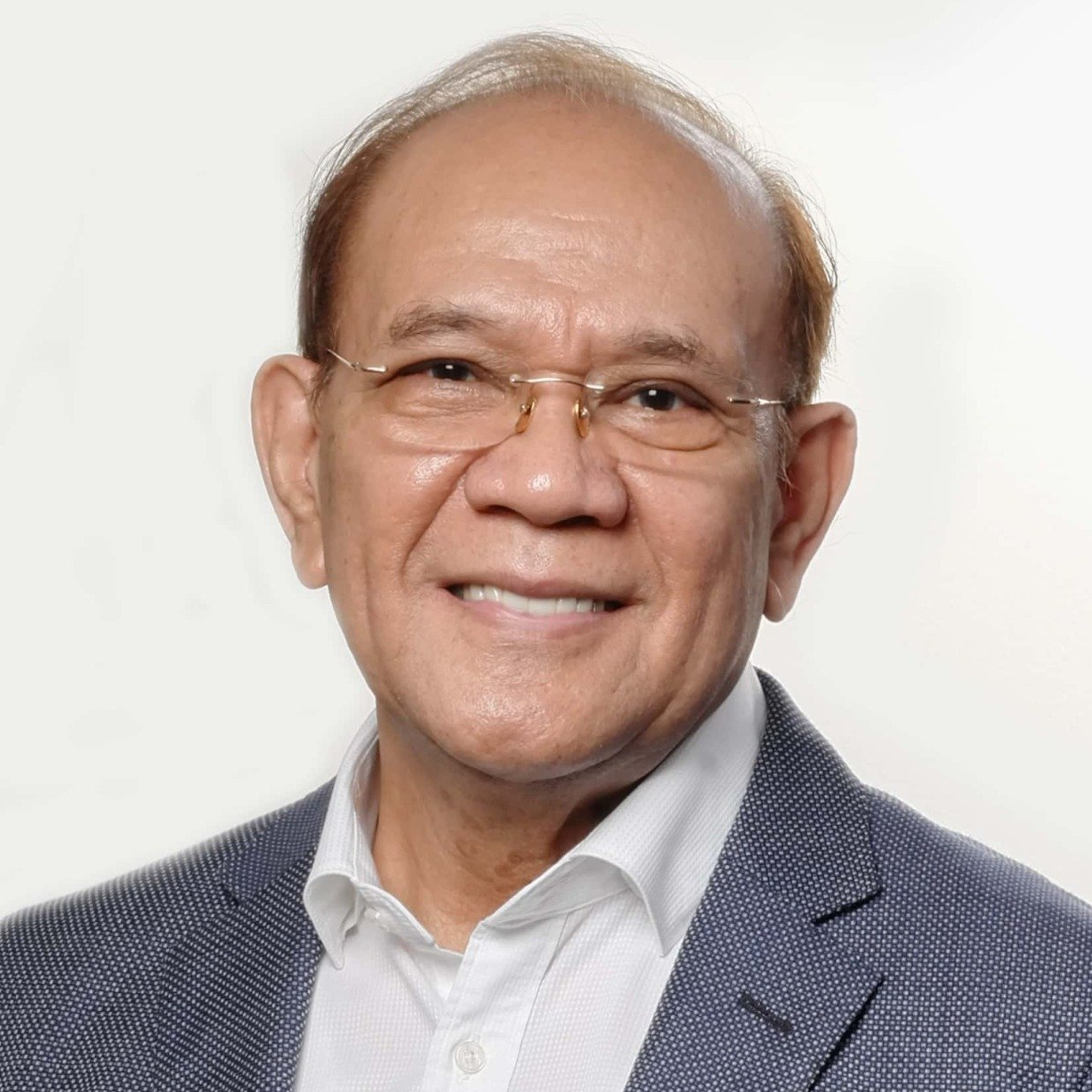 A man wearing glasses and a suit is smiling for the camera.