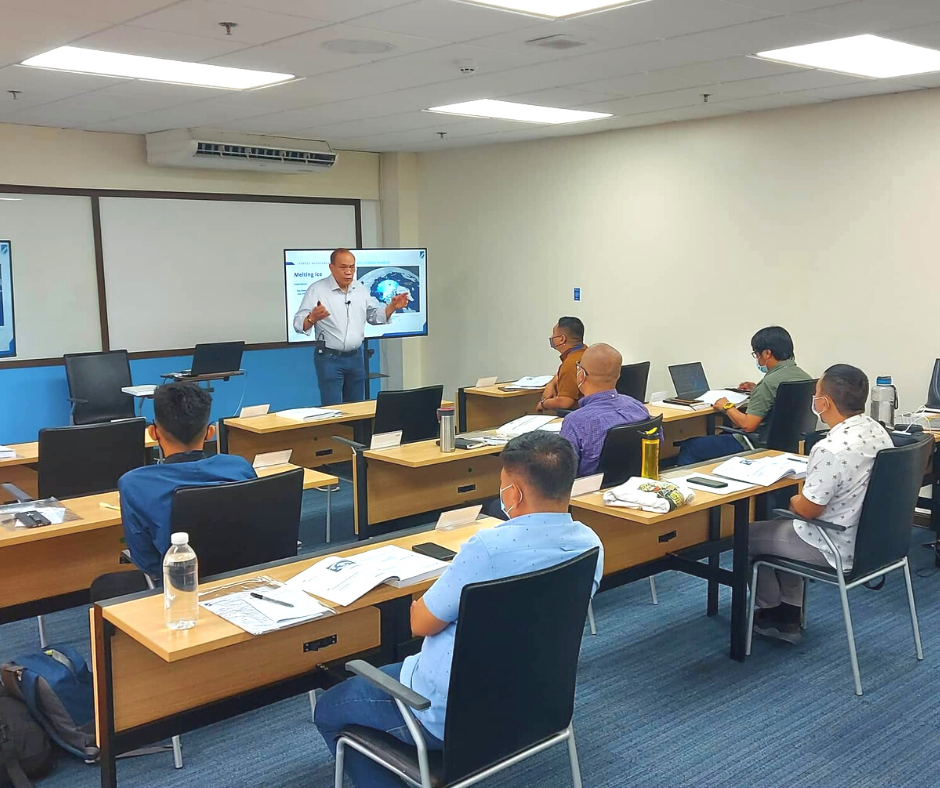 A man is giving a presentation to a group of people in a classroom.