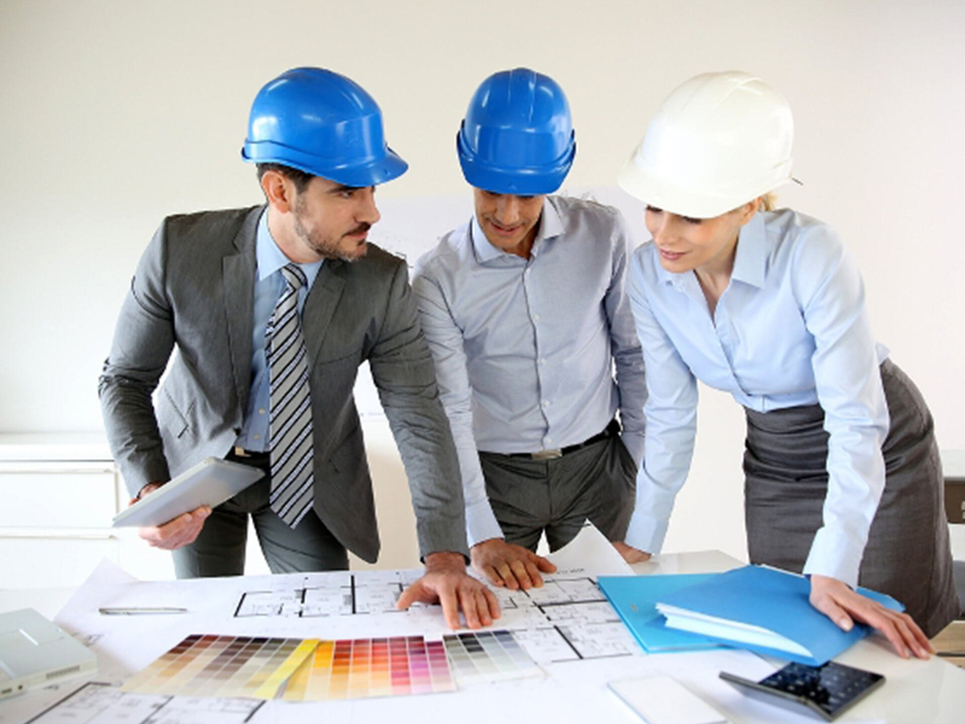 Three people wearing hard hats are looking at a blueprint.